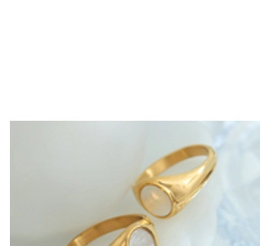 Detailed close-up of golden round ring with white mother of pearl inlay and geometric design