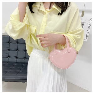 Close-up of pink heart-shaped jelly bag in patent leather worn with a yellow shirt