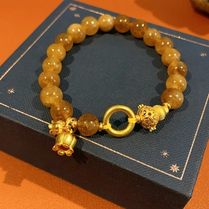 Dettaglio del bracciale di perle citrine con campanellino dorato e ciondoli a sfera cava