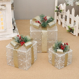Detailed view of three white flocked Christmas gift boxes with gold ribbons and berries