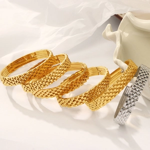 Stacked gold and silver stainless steel bracelets with watch link texture on white background