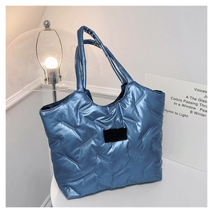 Detailaufnahme der blauen gesteppten Puffer-Tasche mit einem schwarzen Mode-Etikett