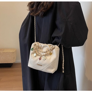 Detail of quilted bucket bag with golden chain and colorful heart enamel charms