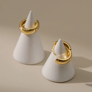 Detailed view of thick gold plated hoop earrings on minimalist jewelry display stands