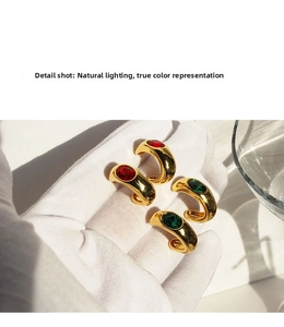 Detailed macro view of vintage gold-plated C-shaped earrings with emerald zircon stones