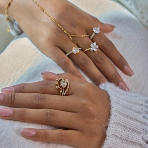 Dettaglio di anelli e bracciali in acciaio dorato 18K con zirconi bianchi su modella