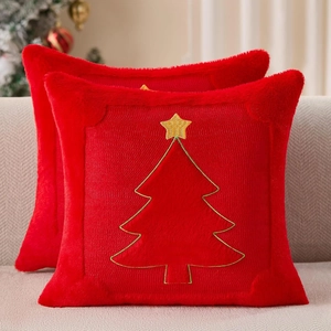 Close-up of two red plush Christmas pillow covers featuring gold embroidered tree patterns