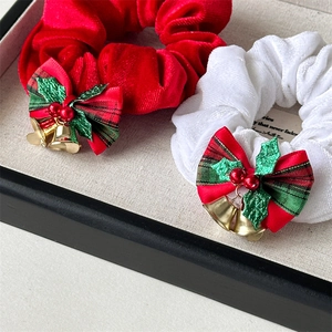 Detail of Christmas velvet scrunchies with plaid bows, holly leaves and gold bells