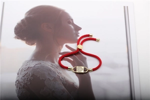 Detail showing red woven rope bracelet with gold zircon heart lock on magazine