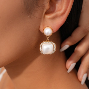 Close-up of vintage drop earrings with pearls and crystal rhinestones on a gold base