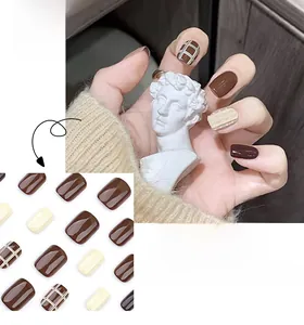 Detail of short square press-on nails featuring dark brown plaid and relief textures