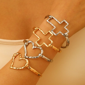 Set of four hammered gold and silver open bracelets with hollow heart and cross charms
