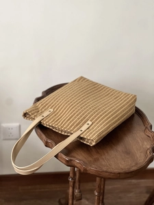 Detail of vintage yellow plaid tote bag with faux leather handle on a wooden side table