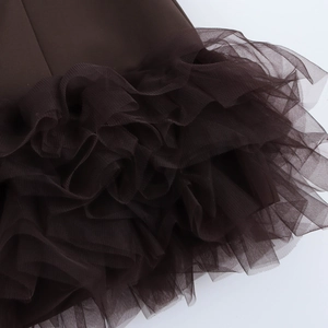 Detailed view of layered brown mesh and organza ruffles on the hem of the dress