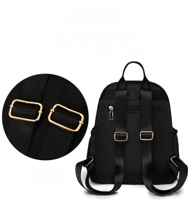 Detail of adjustable shoulder strap with gold metal buckle on black nylon travel backpack