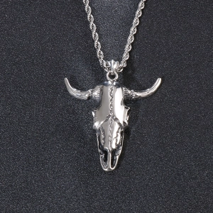 Macro shot of punk style silver bull skull pendant with twisted chain on black texture