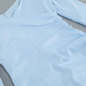 Close-up of sky blue dress featuring fabric covered buttons and elegant side pleats detail
