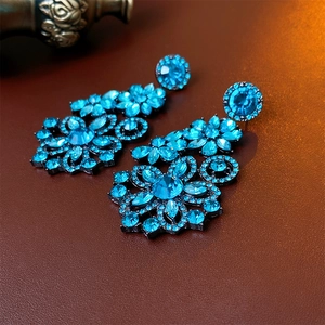 Detail shot of vintage blue crystal flower earrings on a brown leather background