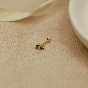 Close-up of golden sterling silver cartilage stud with green and purple gemstones