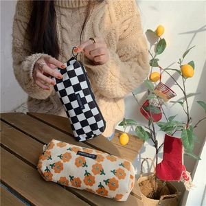 Detail of corduroy pouch with checkerboard and floral patterns and merci label