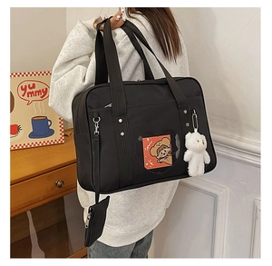 Detail of black JK school bag with heart window and cute plush bear accessory