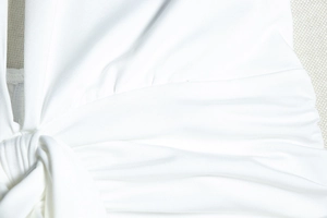 Close-up of the knot design and knitted fabric texture on the white backless dress