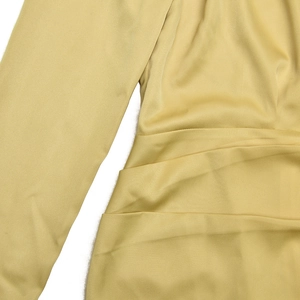 Detailed view of yellow satin dress featuring side ruched draping and long sleeve texture