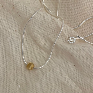 Detail of S925 sterling silver stamp on a minimalist gold bead snake chain necklace