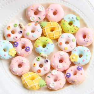 Bunte Donut-Anhänger aus Harz für DIY-Handyhüllen und Haarschmuck auf einem Keramikteller