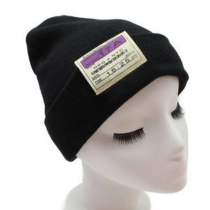 Detailed knit texture of a black beanie with a trendy yellow boarding pass patch