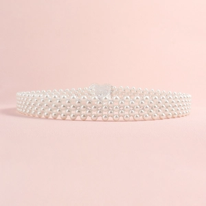 Detail of multi-row pearl waist chain with heart-shaped buckle on pink background