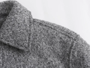 Gros plan sur la texture du tissu bouclé gris au col et à l'épaule de la veste femme