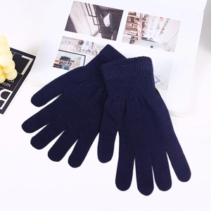 Detailed knit texture of navy blue warm acrylic gloves on white desk background