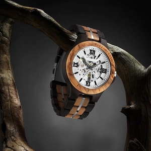 Detail of wooden mechanical watch with skeleton dial hanging on a dry branch