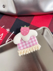 Macro detail of a handmade pink strawberry cupcake hair clip with soft felt and pompom lace