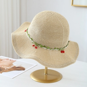 Detail of hand-woven straw hat with floral lace ribbon and small red cherry decorations