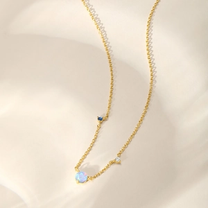 Detail view of gold chain necklace featuring light blue opal and sparkling zircon accents