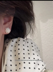 Detailed view of small pearl cluster stud earrings worn on ear with soft luster