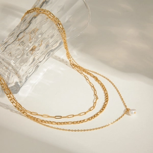Three-layer gold stainless steel necklace with pearl pendant on diverse textured chains
