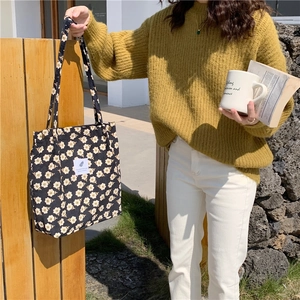 Detalle de bolsa tote de pana floral mostrando el botón a presión y la textura de etiqueta