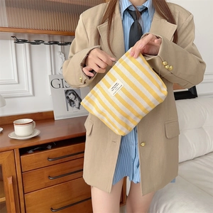 Detail of yellow and white striped toiletry bag with zipper and decorative cloth label