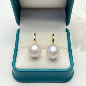Close-up of lustrous freshwater pearl earrings in a dark green velvet jewelry box