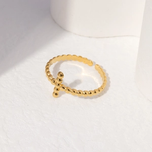 Macro shot of gold beaded cross ring with adjustable band on white minimalist display