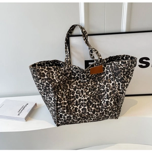 Detail of leopard print canvas tote bag featuring a decorative brown leather logo patch