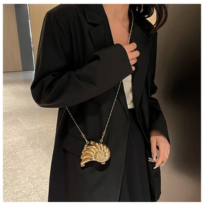 Detailansicht einer goldfarbenen Schnecken-Abendtasche mit eleganter Metallkette
