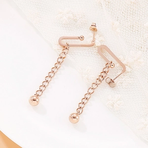 Detailed macro shot of rose gold tassel chain earrings with smooth bead pendants on lace