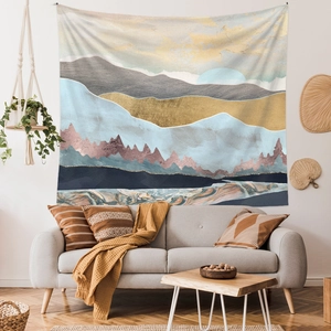 Abstract mountain landscape tapestry hung above a modern sofa in a cozy living room scene