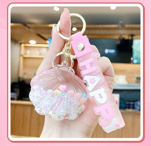 Close-up of pink shell liquid keychain with glitter and silicone Happy strap held in hand