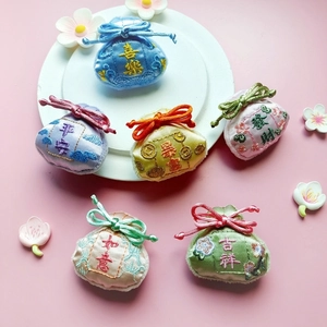 Embroidered Chinese fortune pouches set in various colors on a white plate