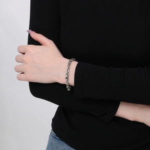 Détail d'un bracelet gourmette en argent poli porté au poignet par un mannequin